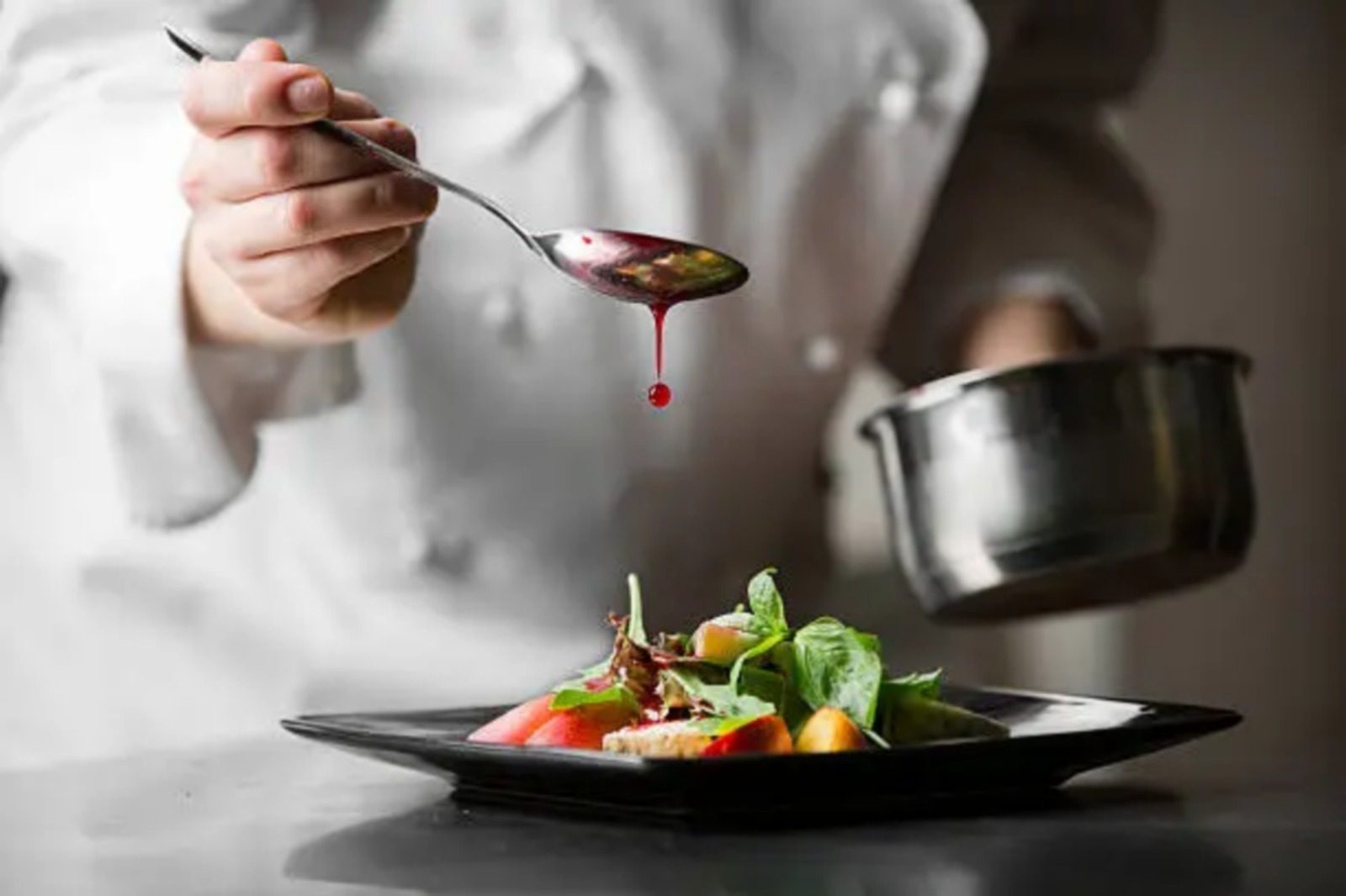 Chef che rifinisce un piatto con la salsa