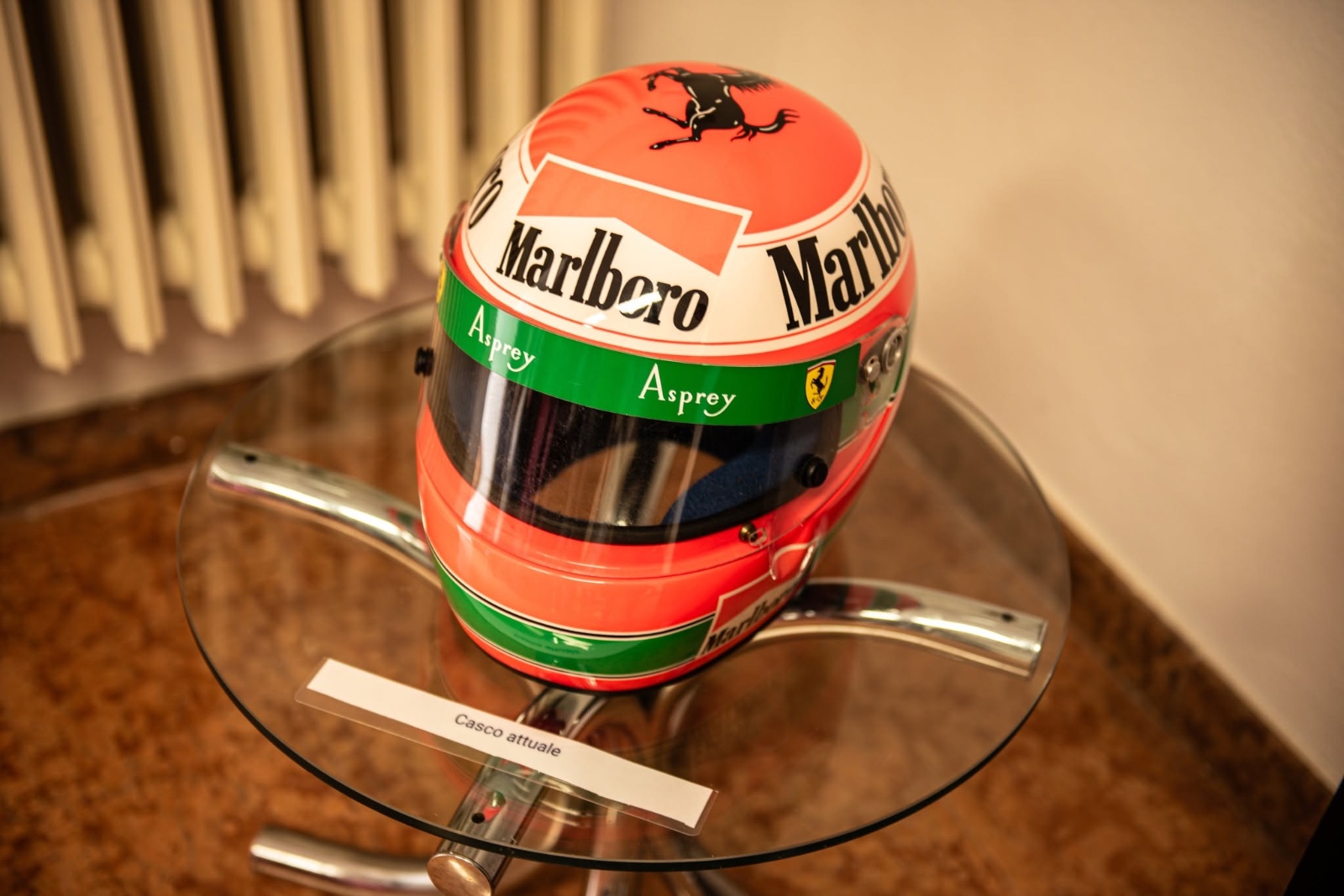 Un casco da Formula 1 rosso esposto nel Museo del Casco con il cartellino «Casco attuale»