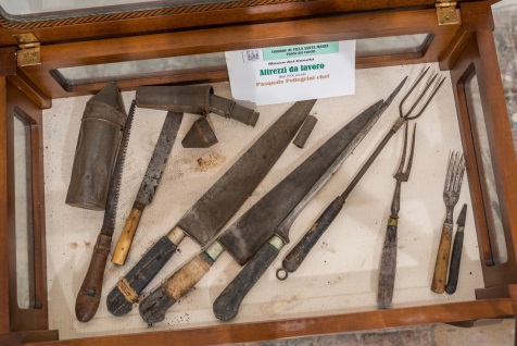 Coltelli, forchettoni e attrezzi da cucina antichi in una vetrina del Museo dei Cuochi
