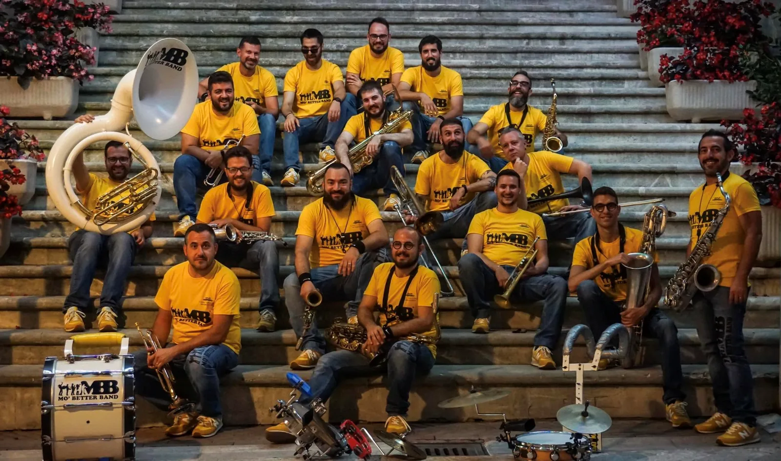 La Mo’ Better Band in maglietta gialla con gli strumenti, seduta su una scalinata