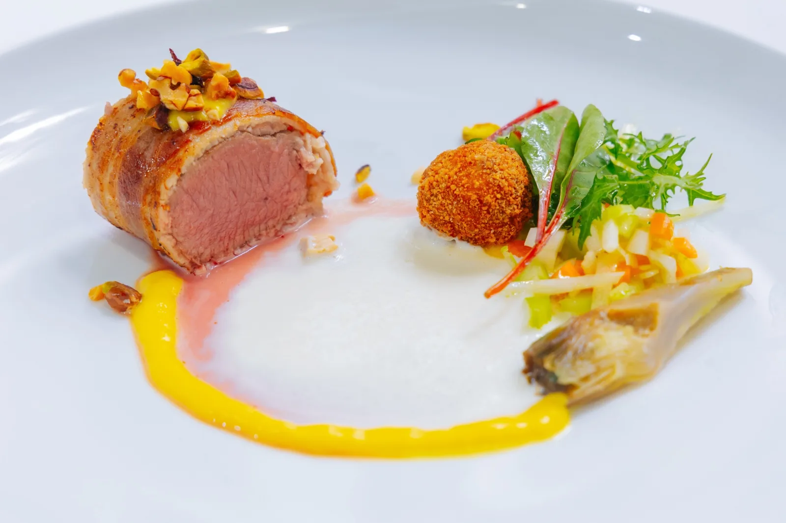 Rotolo di vitello avvolto nel bacon con granella di pistacchio, crocchetta e insalatina