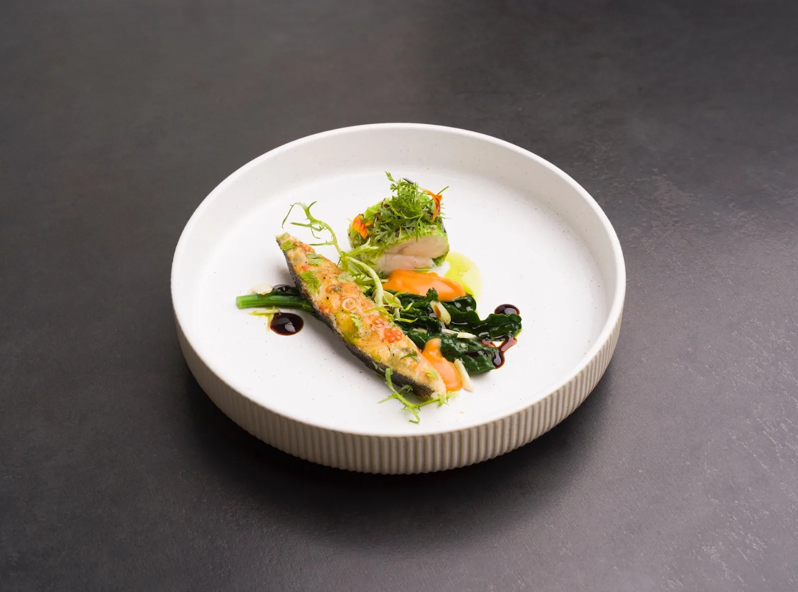 Trancio di pesce spada alle erbe con verdure saltate, salsa arancione e riduzione scura